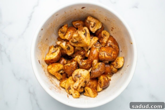 A white bowl full of marinated mushrooms on a white marble counter