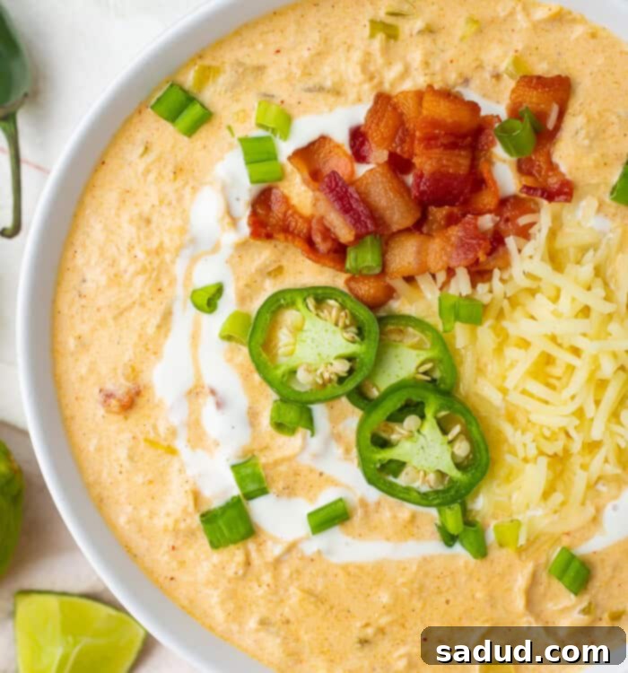 A bowl of keto white chicken chili topped with jalapeno slices and bacon, showcasing its rich, creamy texture and delicious toppings.