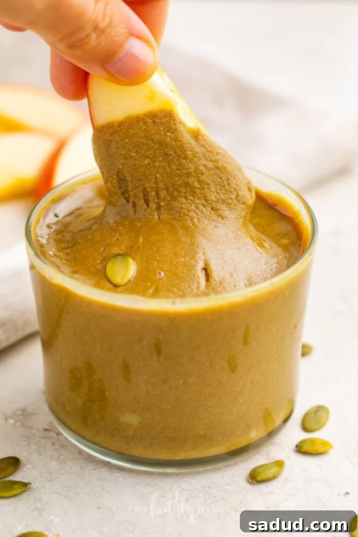An apple slice dipped in pumpkin butter in a glass cup