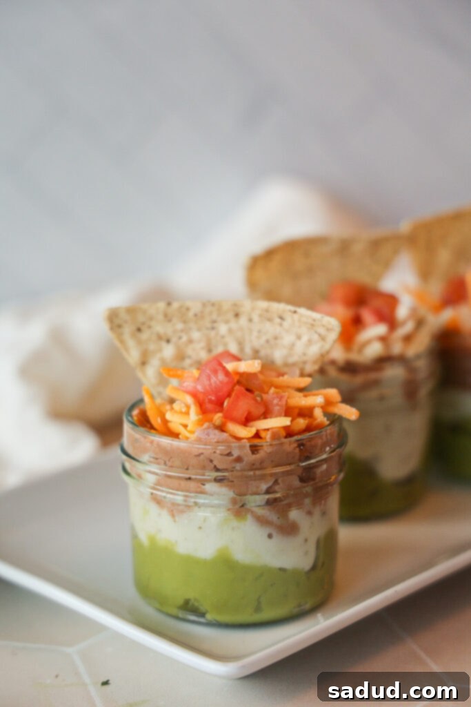 A collection of individual 7 layer dip cups, ready for a party.