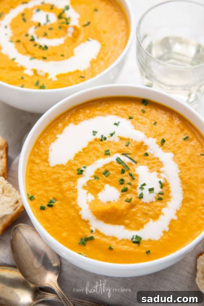 Overhead shot of two bowls of pumpkin bisque garnished with cream and chives, a perfect fall soup.