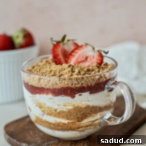 A close-up of a delightful Strawberry Cheesecake Yogurt Parfait, garnished with fresh strawberries and cookie crumbles, ready to be served.