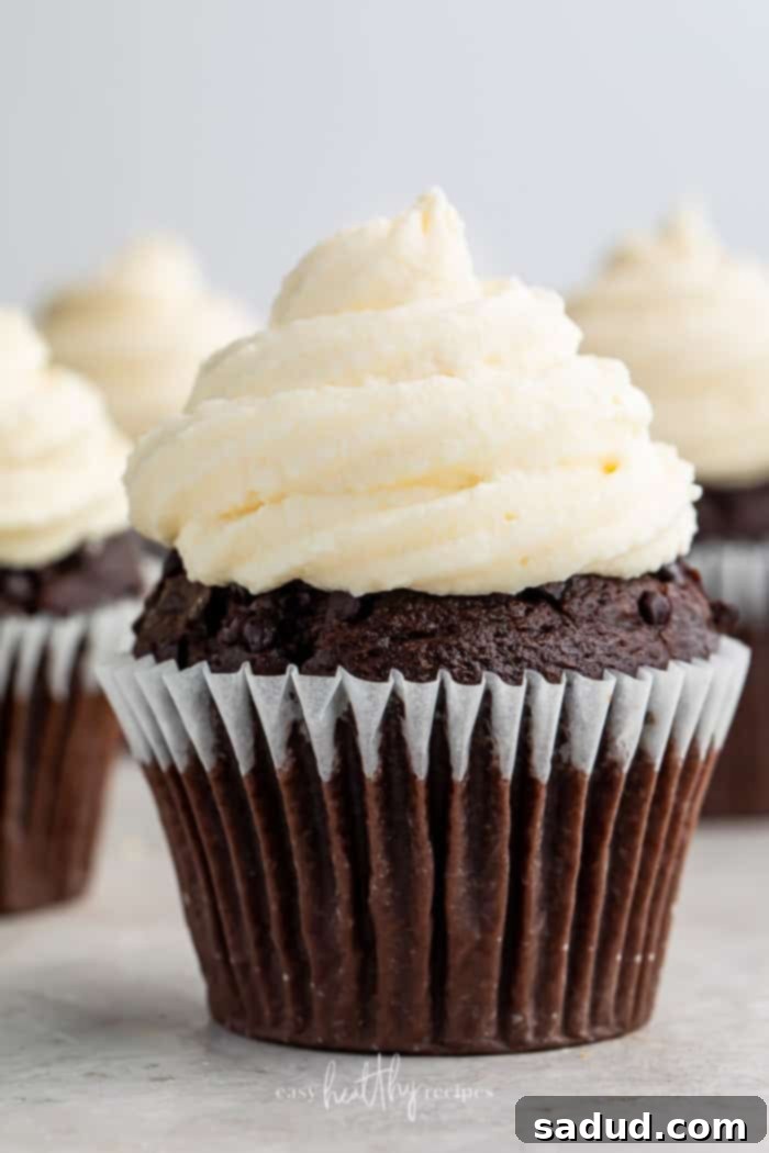 A chocolate cupcake with a generous swirl of fluffy keto cream cheese icing, sitting in a paper liner.
