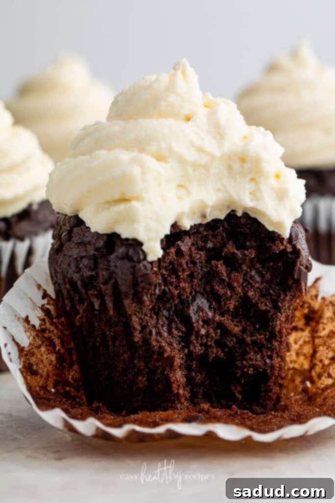 A delicious keto chocolate cupcake topped with rich cream cheese icing, with a bite taken out, showing the fluffy texture.