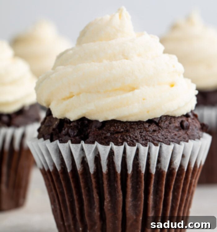 A chocolate cupcake with fluffy keto cream cheese icing in a paper wrapper.