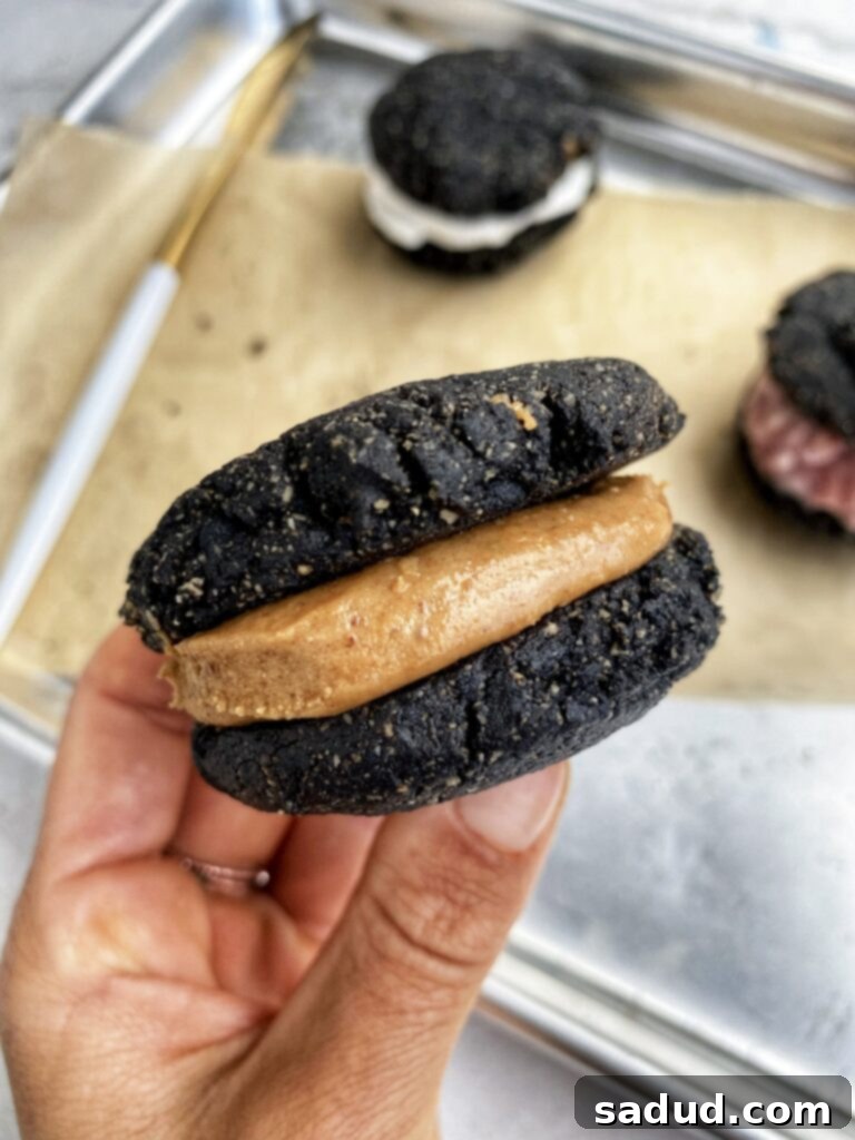 A close up of a peanut butter stuffed Oreo. Two halves of a dark chocolate cookie with creamy peanut butter filling in between.