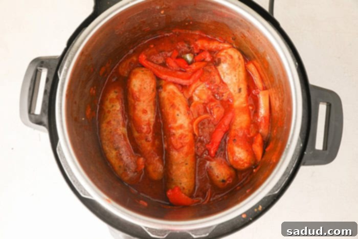 Adding vegetables, wine, and seasonings to the browned sausages and aromatics in the Instant Pot.