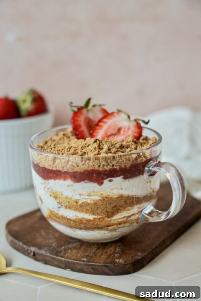Layered vegan strawberry cheesecake yogurt parfait, a sweet and high protein snack.