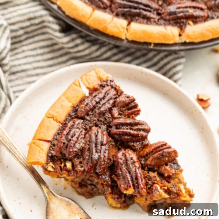 A wedge slice of gluten free pecan pie on a plate next to the remaining pie in a pie plate.