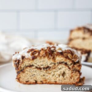 A delicious slice of Cinnamon Swirl Banana Bread with a creamy glaze and streusel topping.