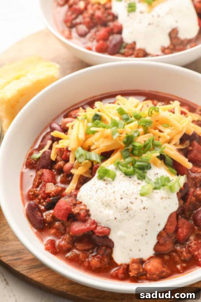 A bowl of bison chili topped with sour cream, cheese, and scallions