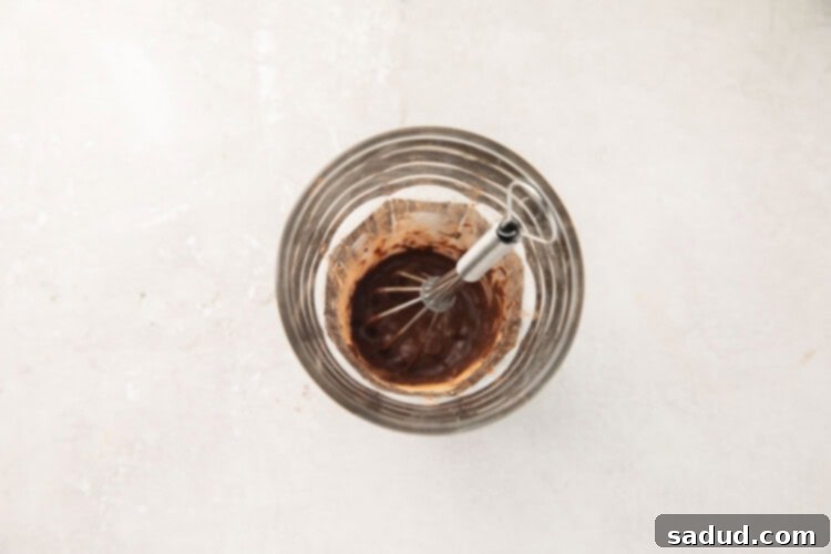 Hot water and cocoa powder are mixed together to form a rich chocolate paste.