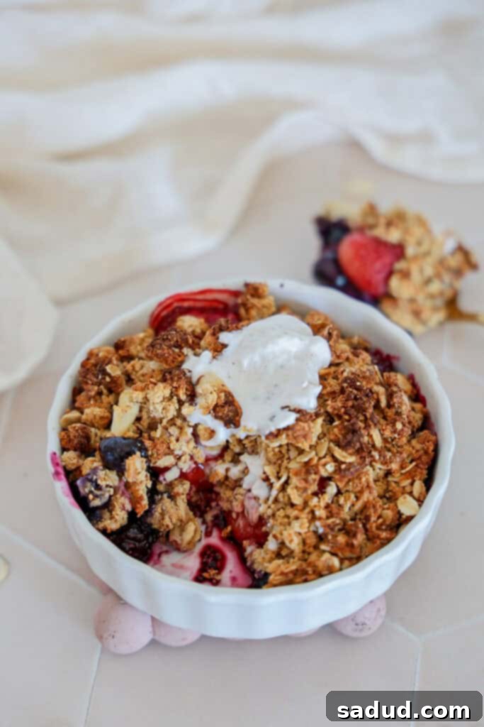 A bite out of a berry breakfast crumble, showcasing the fruit and crunchy topping.