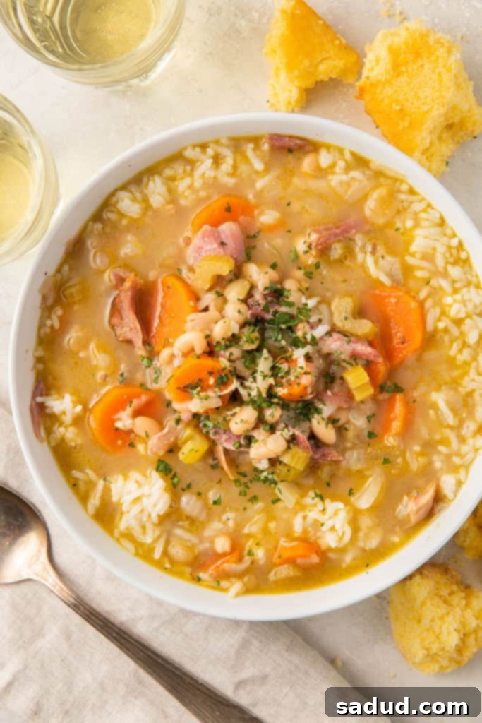 Bowl of smoked turkey soup with carrots, celery, and beans on a white table