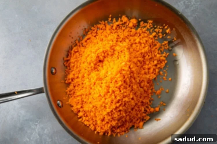 Sweet potato rice, oil, and seasoning in a large silver skillet.