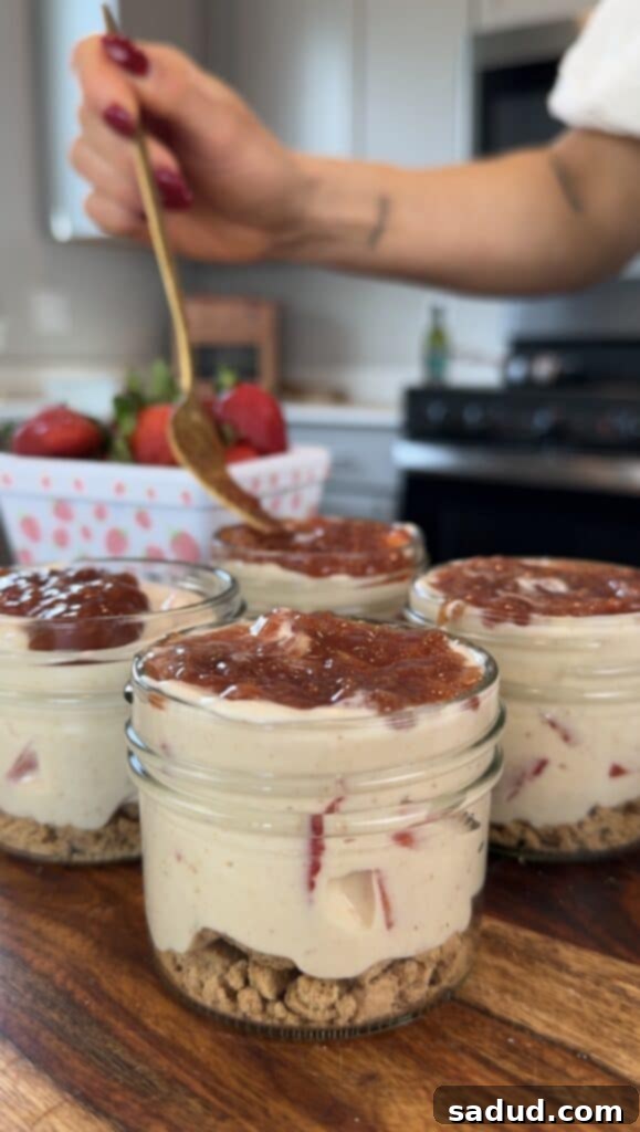 Finished strawberry cheesecake parfaits with toppings in mason jars.