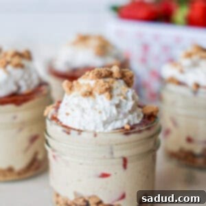Strawberry Cheesecake Parfait in a glass jar, topped with whipped cream and fresh berries.