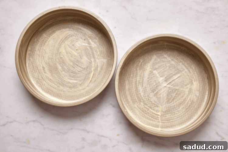 Two buttered and lined cake pans ready for batter.