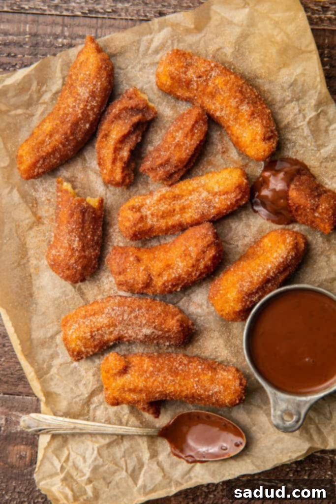 Guilt-Free Churros 2 Keto churros next to a small bowl of chocolate sauce with a chocolate covered spoon on parchment paper