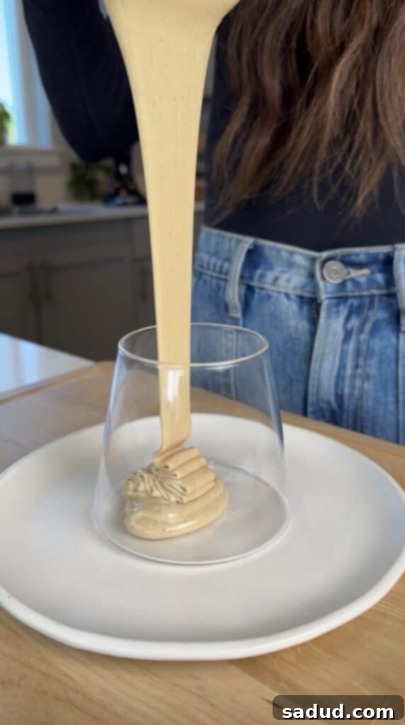 An in-progress shot of a stand mixer whisking honey, clearly showing the lightening color and increasing volume as it whips.