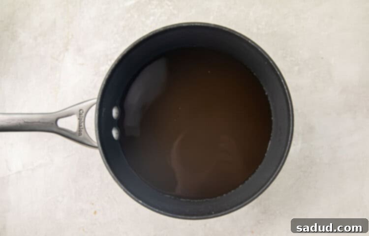 Broth and water simmering in a silver pot on the stovetop.