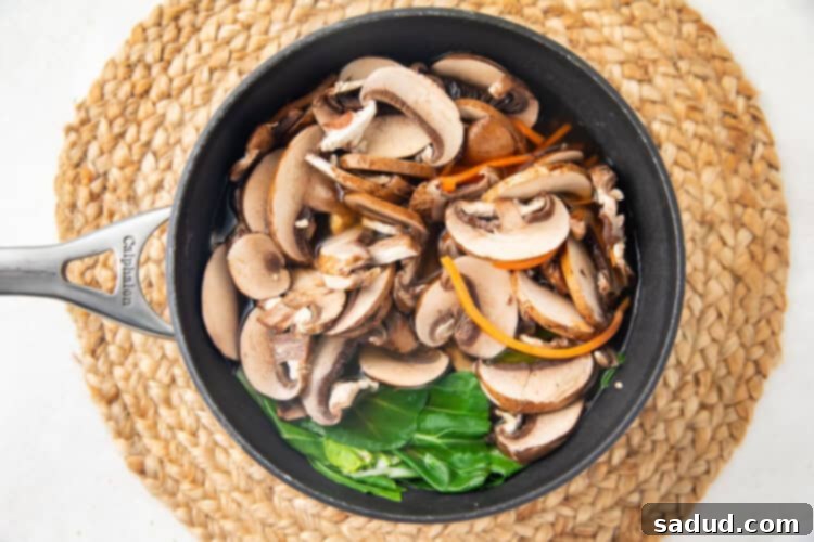 Chinese vegetable soup with bok choy, carrots, and mushrooms simmering in a silver pot.