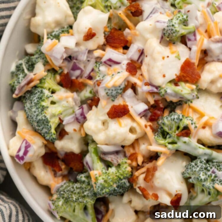 A large white bowl of homemade Amish broccoli salad, featuring crunchy broccoli and cauliflower florets, savory bacon bits, and grated cheddar cheese, all coated in a rich, creamy dressing.