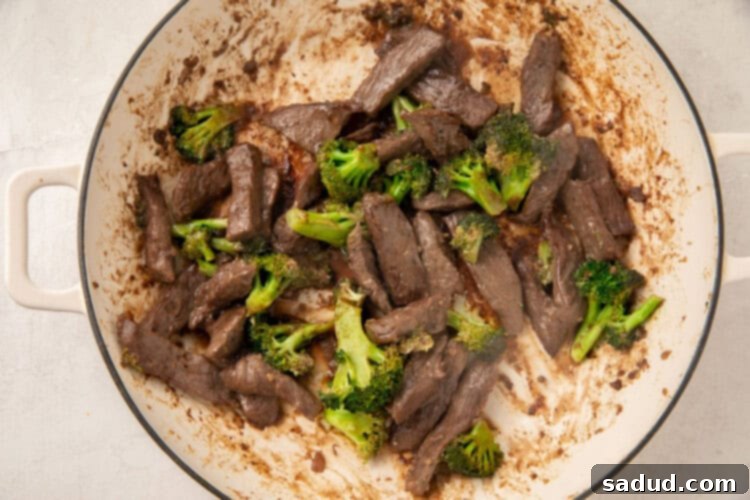 Beef and broccoli cooking together in a large skillet
