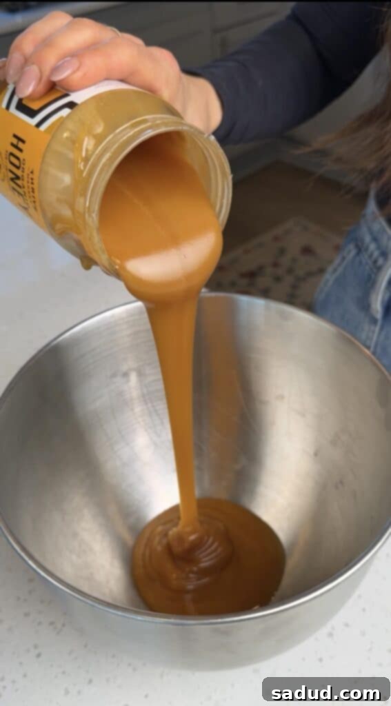 Honey being whipped in a stand mixer, showing a light and airy texture starting to form.
