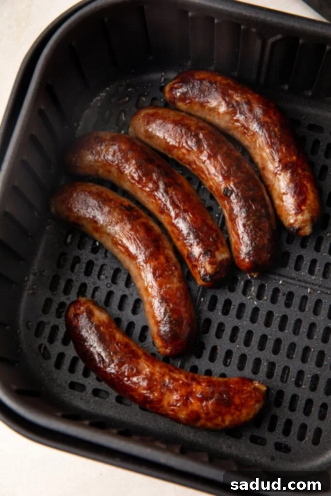 Cooked sausages resting in an air fryer basket after cooking