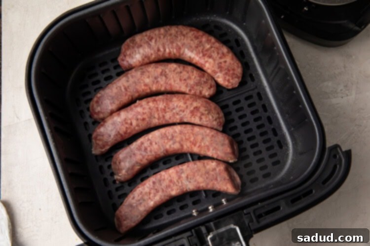 Uncooked sausages arranged in an air fryer basket