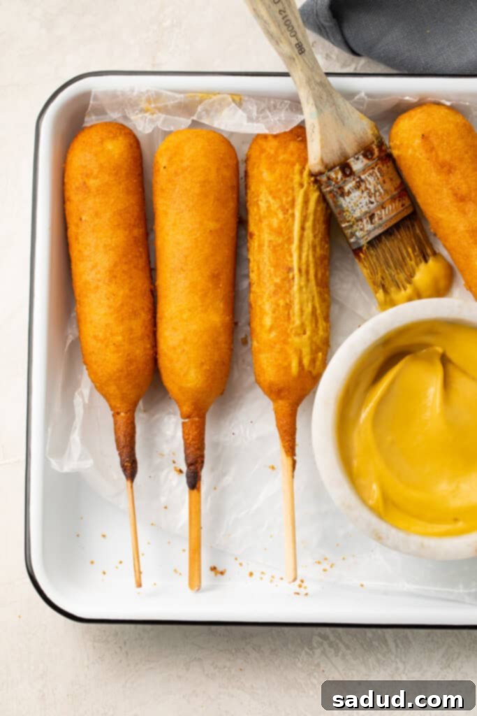 Air Fryer Corn Dogs 3 Air fryer corn dogs on a tray next to a bowl of mustard