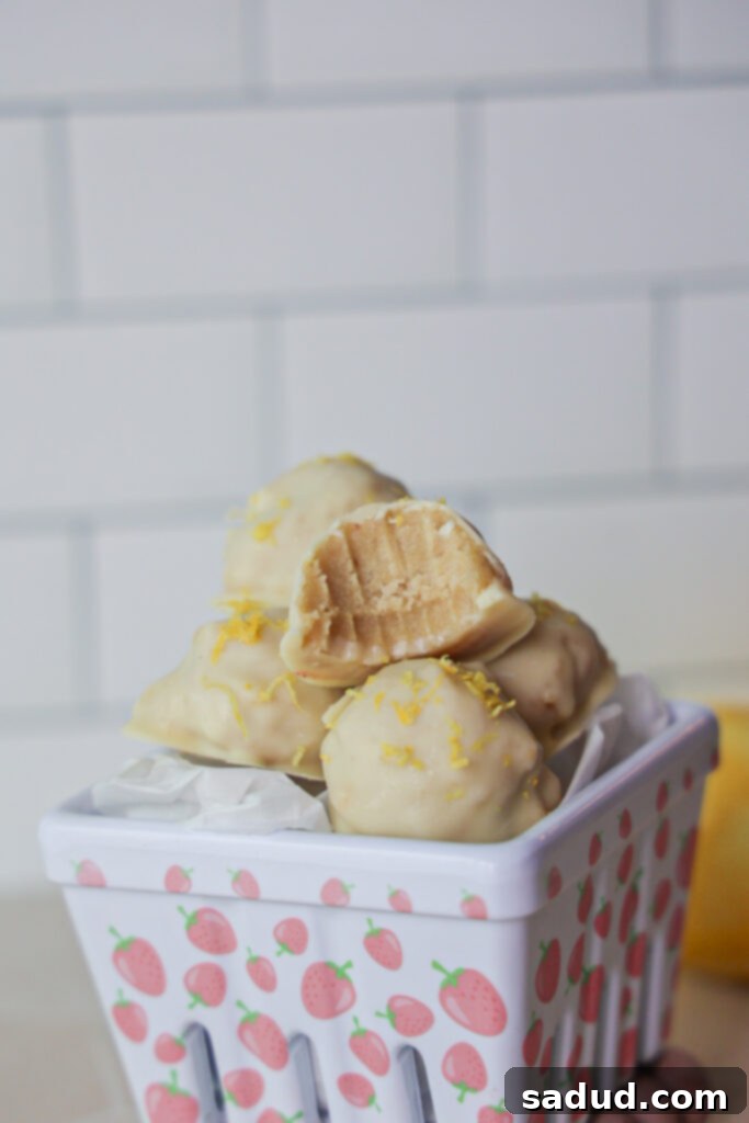 Vegan, no bake, sugar cookie lemon truffles coated and garnished with lemon zest, ready to eat.
