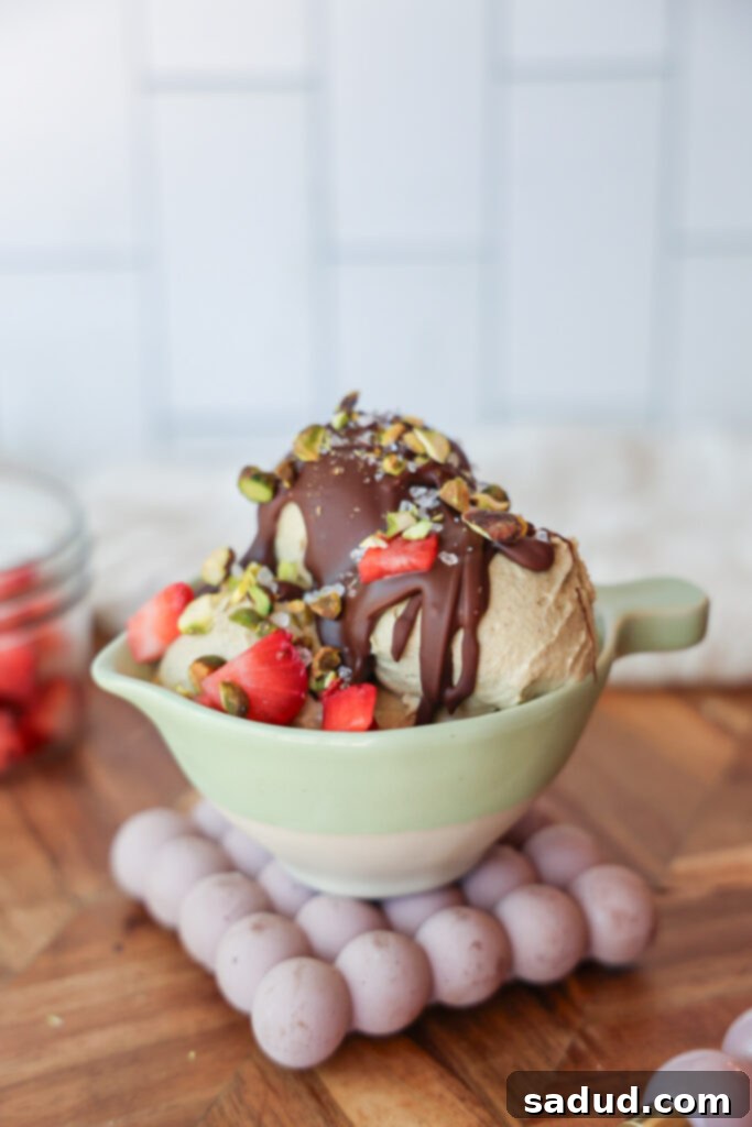 Ninja Creami Vegan Pistachio Perfection 2 A bowl of vegan pistachio ice cream with chocolate shell and strawberries.