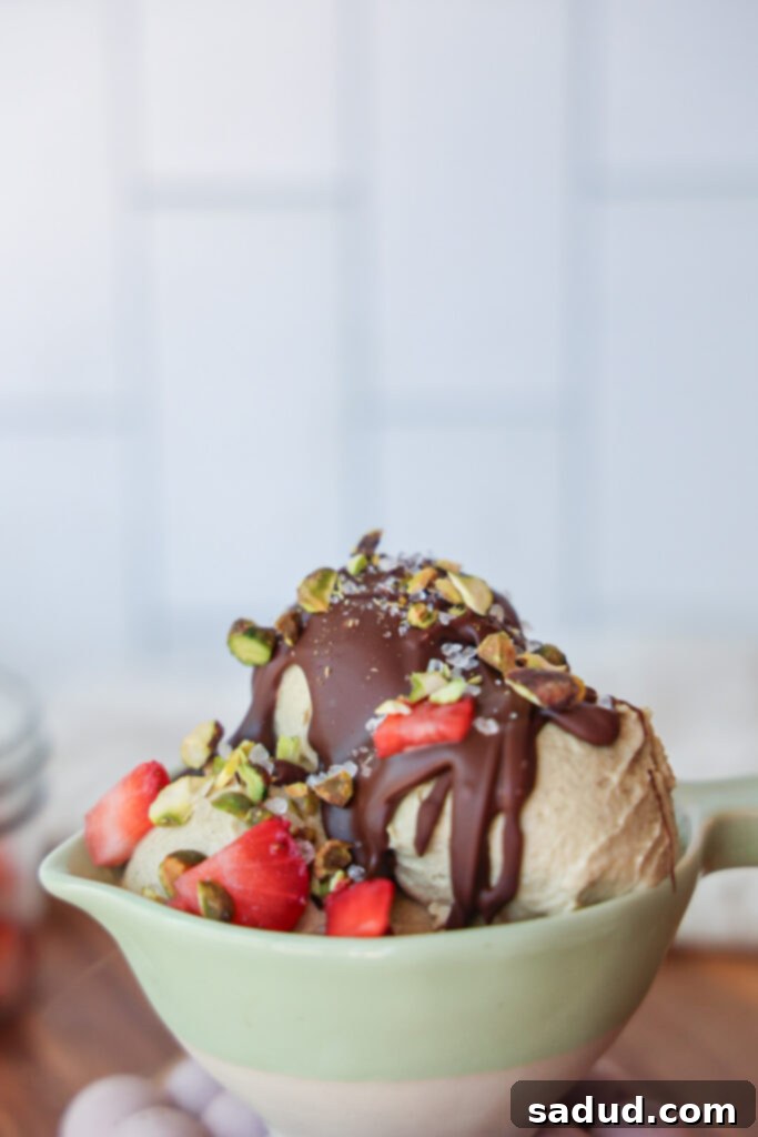 Ninja Creami Vegan Pistachio Perfection 3 A bowl of pistachio ice cream with chocolate magic shell and strawberries.