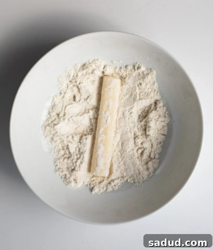 Mozzarella stick being coated in gluten-free flour