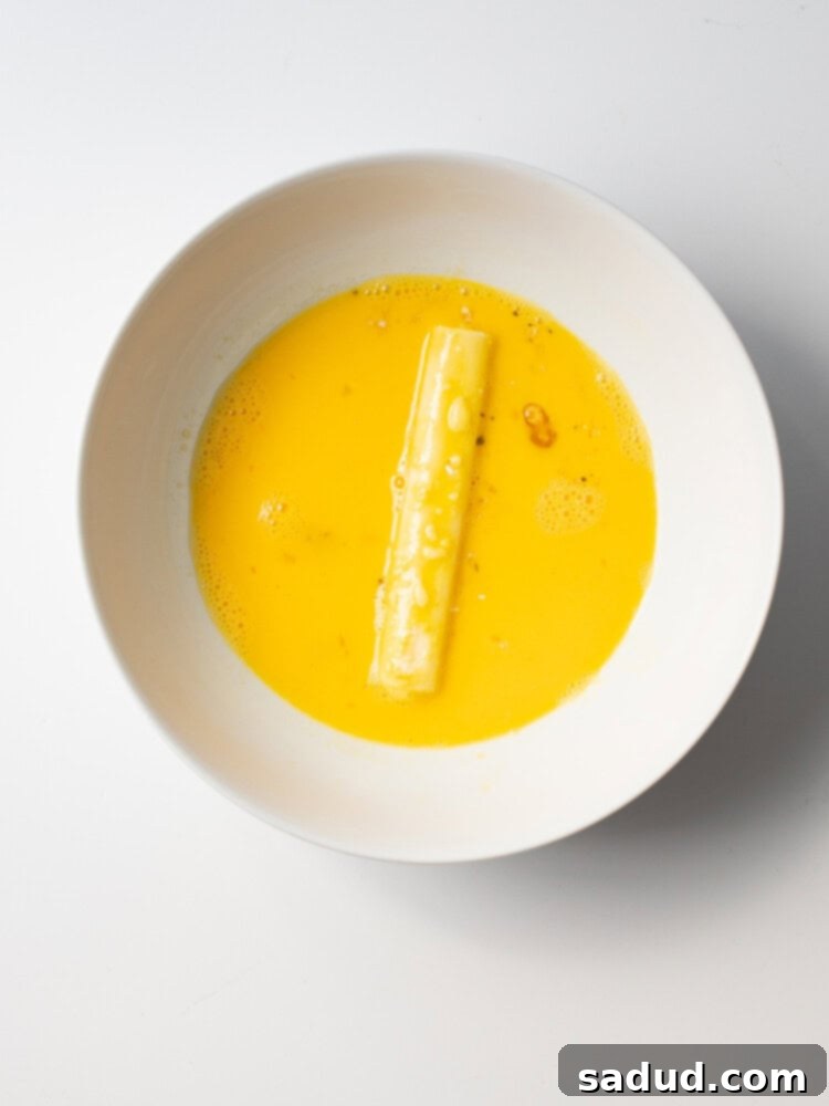 Flour-coated mozzarella stick dipped in egg wash