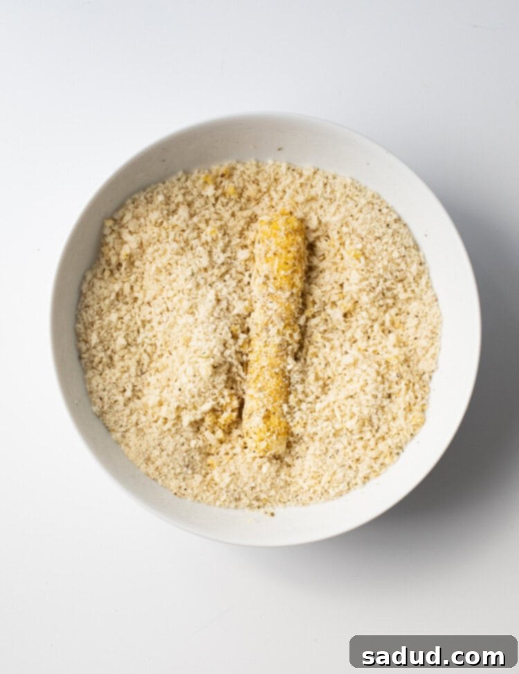 Gluten-free mozzarella stick receiving a second coating of gluten-free breadcrumb mixture