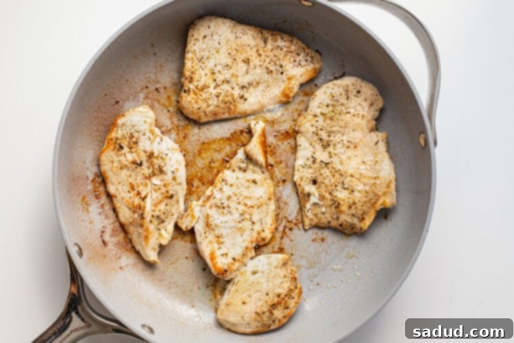 Chicken cutlets in a large grey skillet.