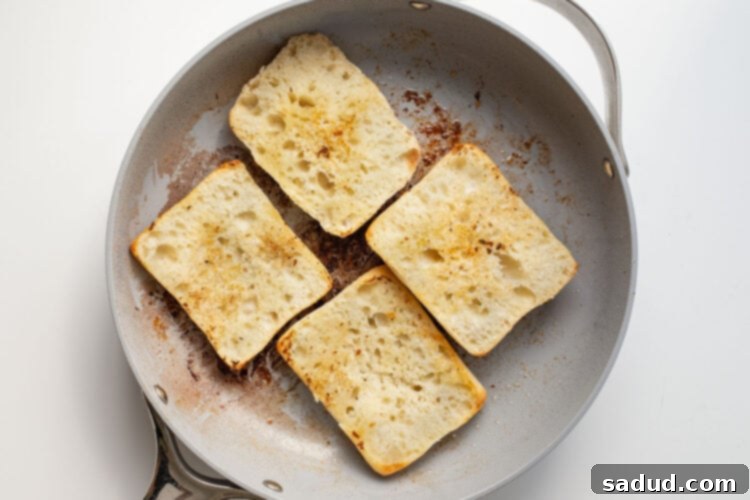 Halved ciabatta rolls in a large grey skillet.