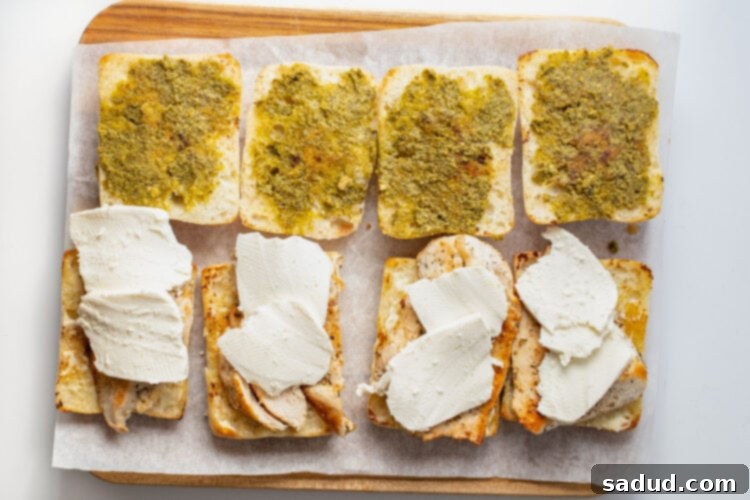 Slices of mozzarella placed on top of chicken cutlets for chicken pesto sandwiches.