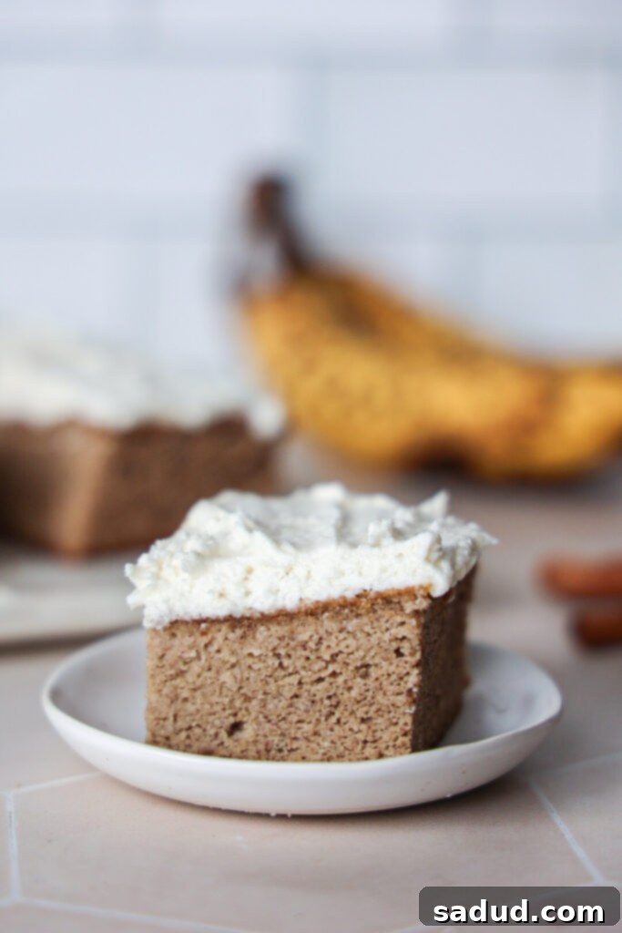 A single frosted banana bar on a white plate, showcasing its moist texture.