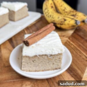 Frosted Banana Bread Bars on a plate with frosting, cinnamon, and fresh banana slices.