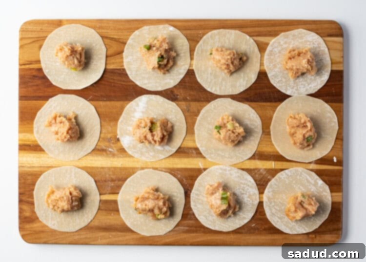 Wonton wrappers on a cutting board, filled with chicken gyoza filling