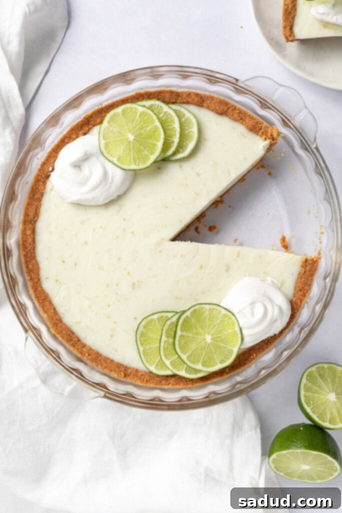 Slice of creamy vegan key lime pie topped with coconut whipped cream.