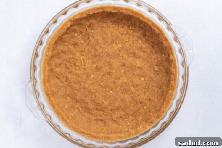 Crust for vegan key lime pie being pressed into a pie dish.