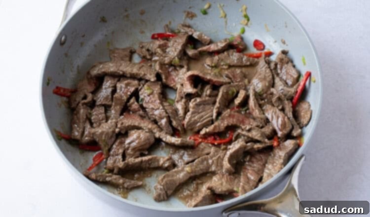 Thinly sliced beef in skillet with garlic and red chilis