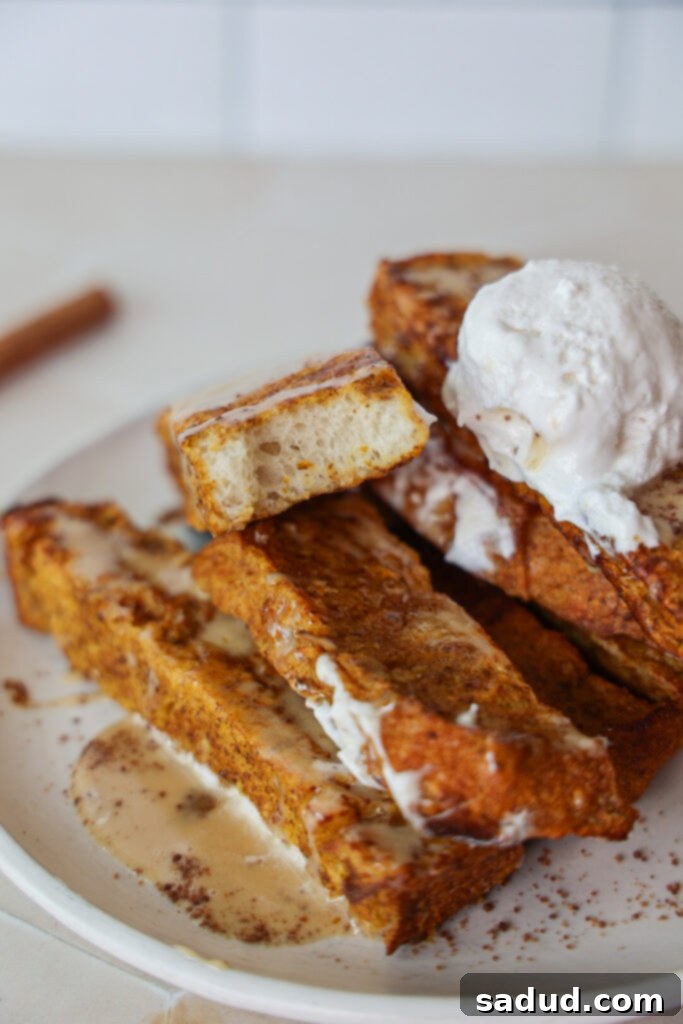A plate of golden pumpkin spice french toast sticks adorned with fluffy coconut whipped cream, crunchy pecans, and a sweet drizzle of maple syrup.