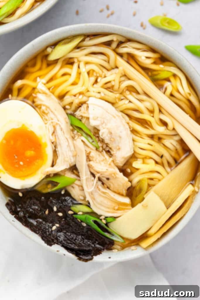 Spicy Chicken Ramen in a bowl topped with a soft boiled egg, scallions, and sesame seeds. A vibrant and appealing dish ready to be enjoyed.