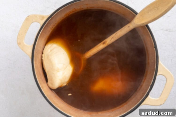 Chicken breasts simmering in the spicy ramen broth